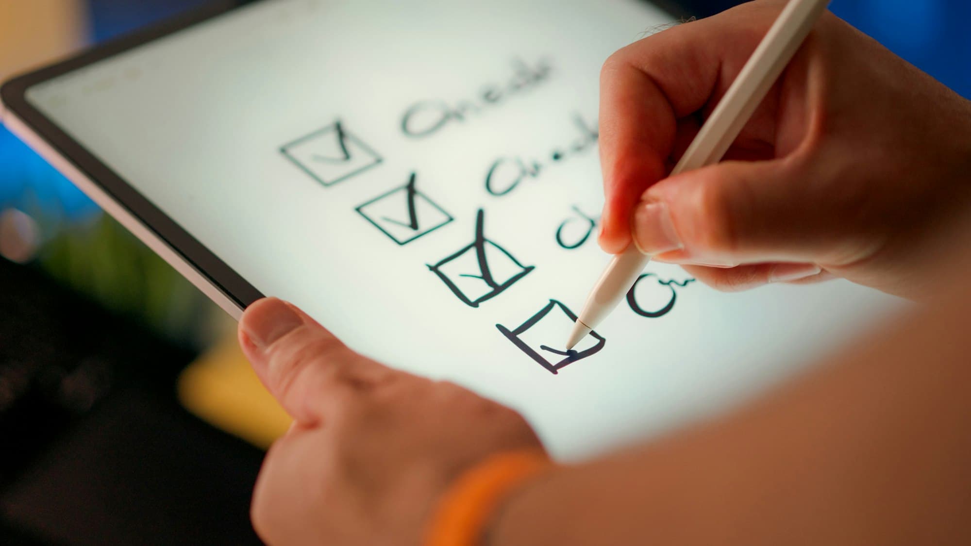 A hand uses a stylus to tick boxes on a checklist displayed on a tablet